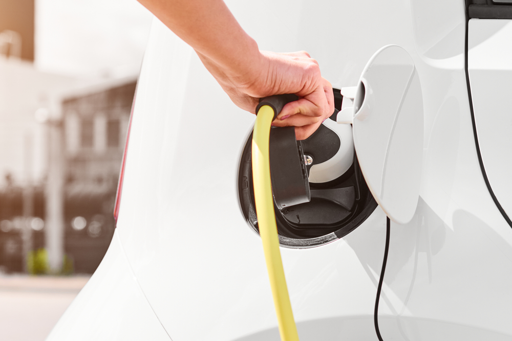 woman,unplugging,a,charger,from,an,electric,car,socket.,eco
