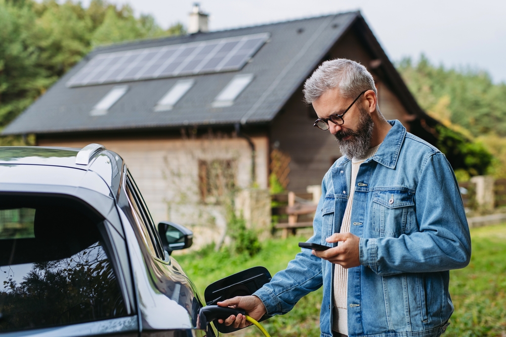 man,charging,electric,car,in,front,of,his,house,,plugging